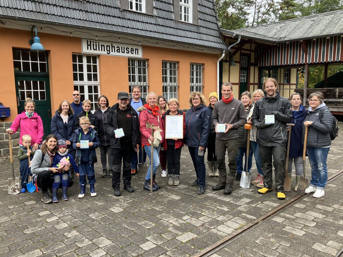 Gruppenfoto mit Urkunden und Spaten vor dem Bahnhof Hüinghausen bei einer gemeinsamen Aktion