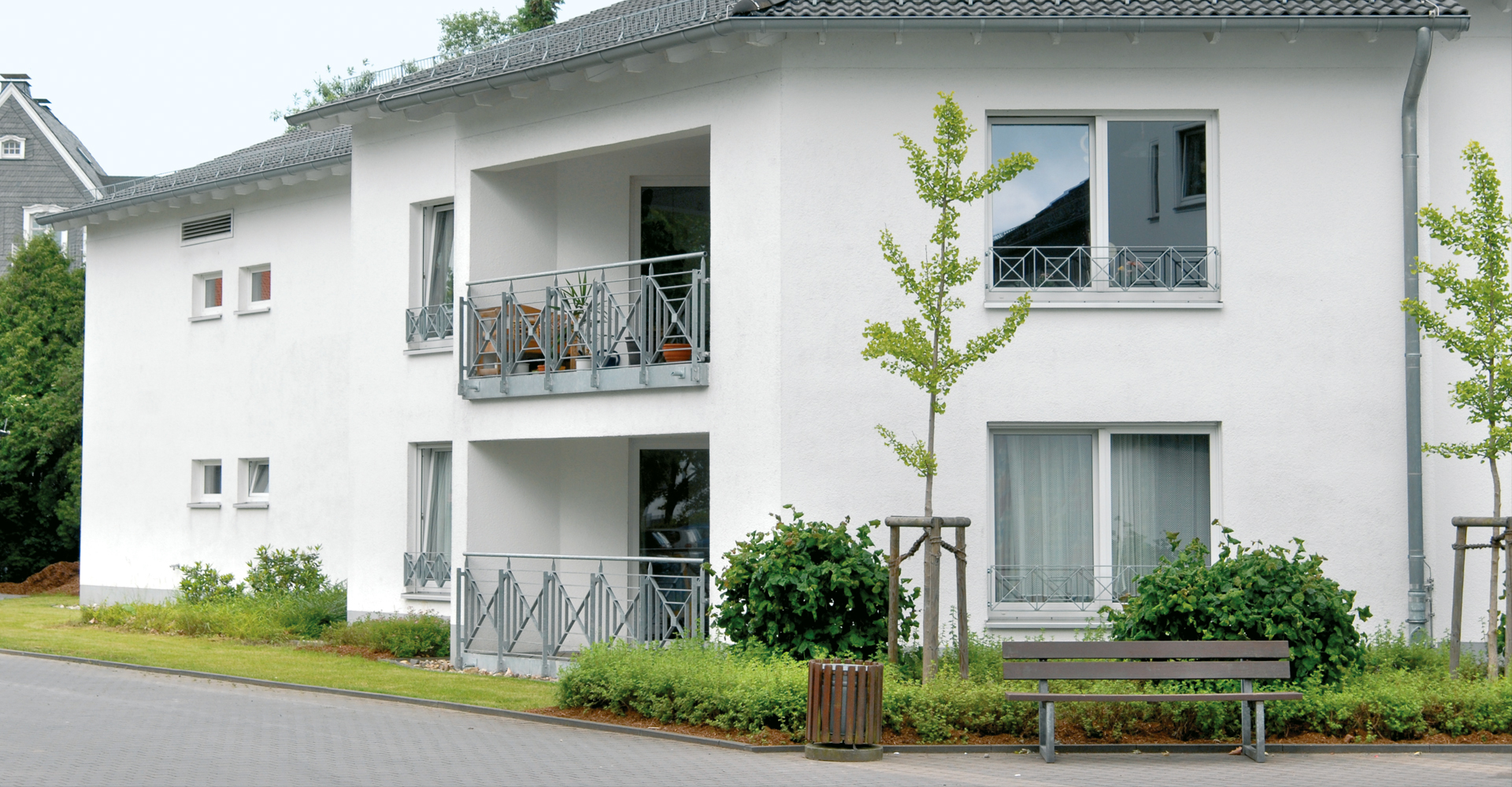 Außenansicht eines hellen Wohngebäudes mit Balkonen und Grünanlage