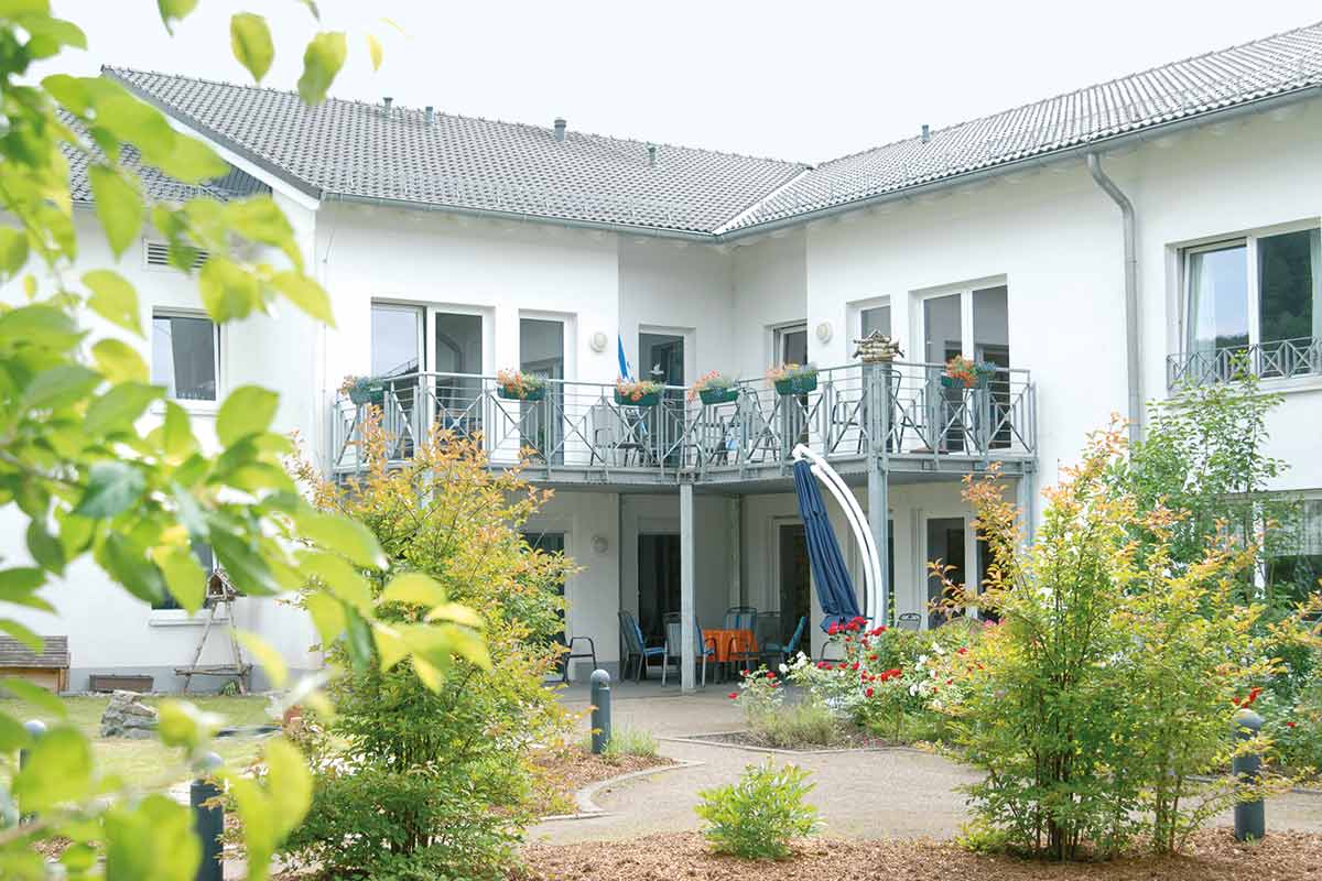 Außenansicht des Altenzentrums St. Josef mit mehrstöckigen Balkonanlagen, Sitzbereichen und umliegender Begrünung.